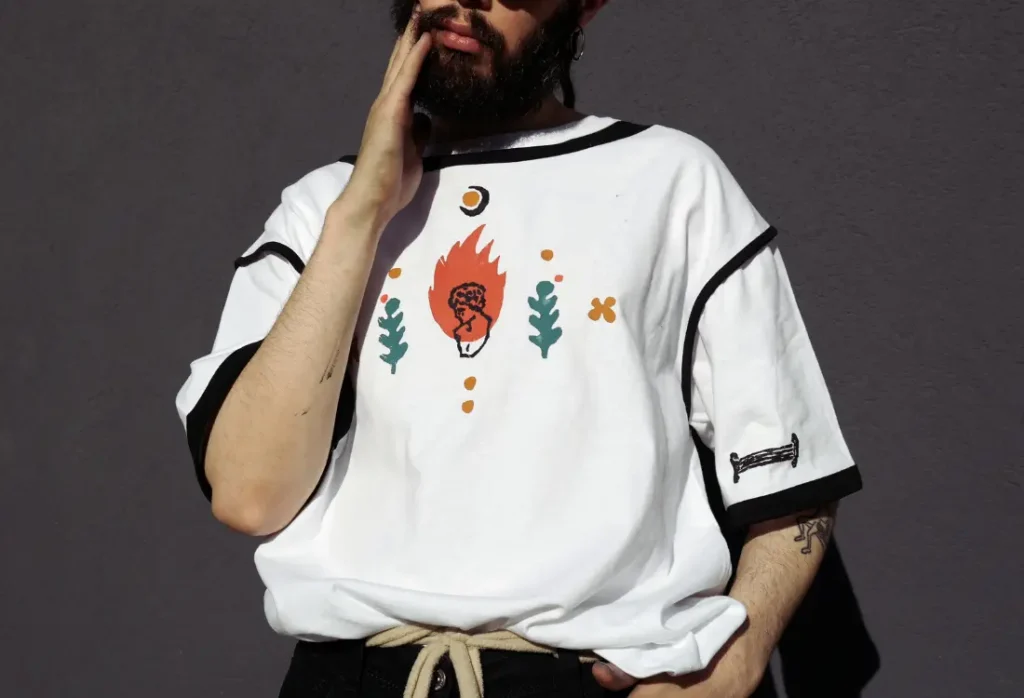 White custom t-shirt featuring a minimalist illustrated artwork in orange, green and black, inspired by contemporary gallery merchandise.
