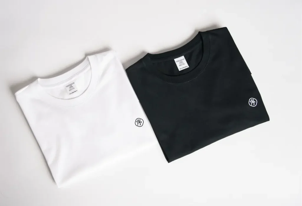 White and black embroidered t shirts with a small left chest logo, showcasing premium custom shirt embroidery and professional logo placement.
