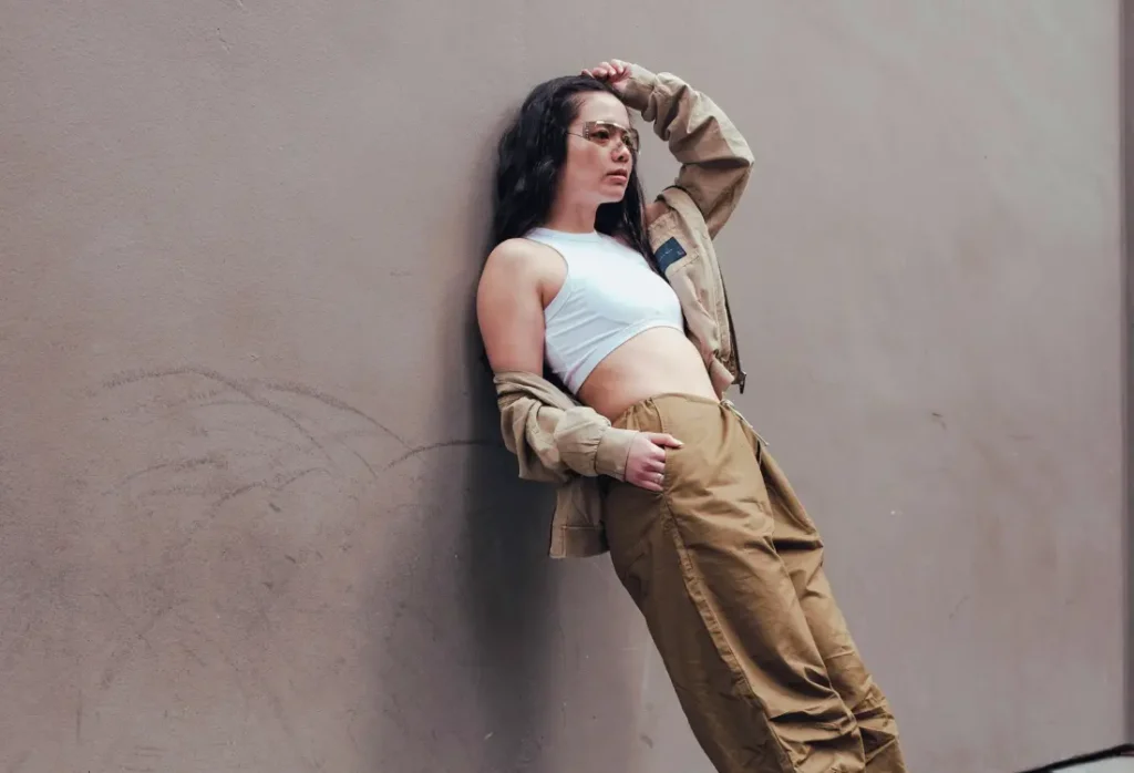 Woman in modern athleisure wear styled with a white sports bra and durable designer-inspired trousers in an urban environment.