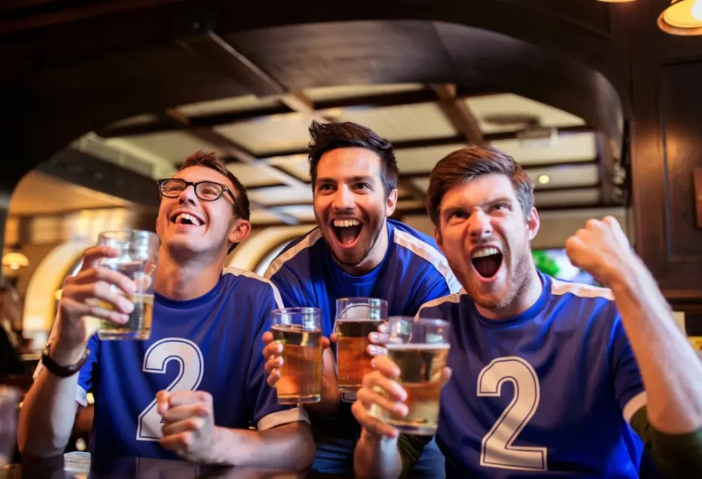 Friends in comfortable numbered T-shirts cheering together while watching a game.