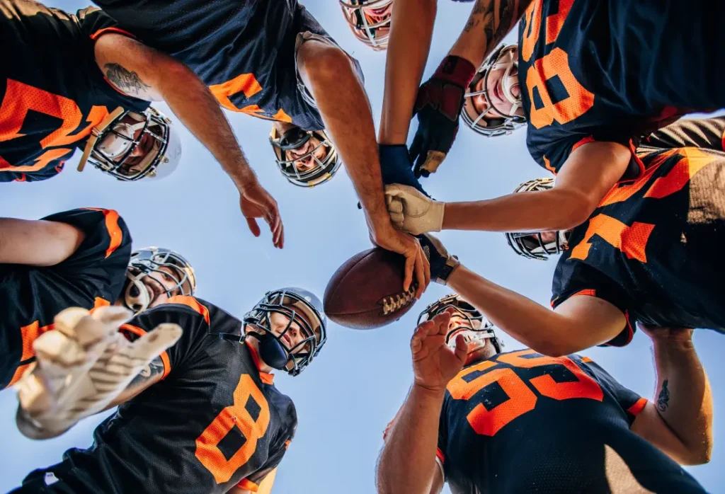 American football jerseys have a distinct design. A group of players on the field with jerseys with large numbers and stripes.