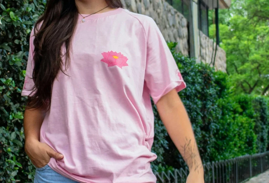 Woman dressed in a pink graphic T-shirt with a small chest print and a sleeve logo with baggy pants.