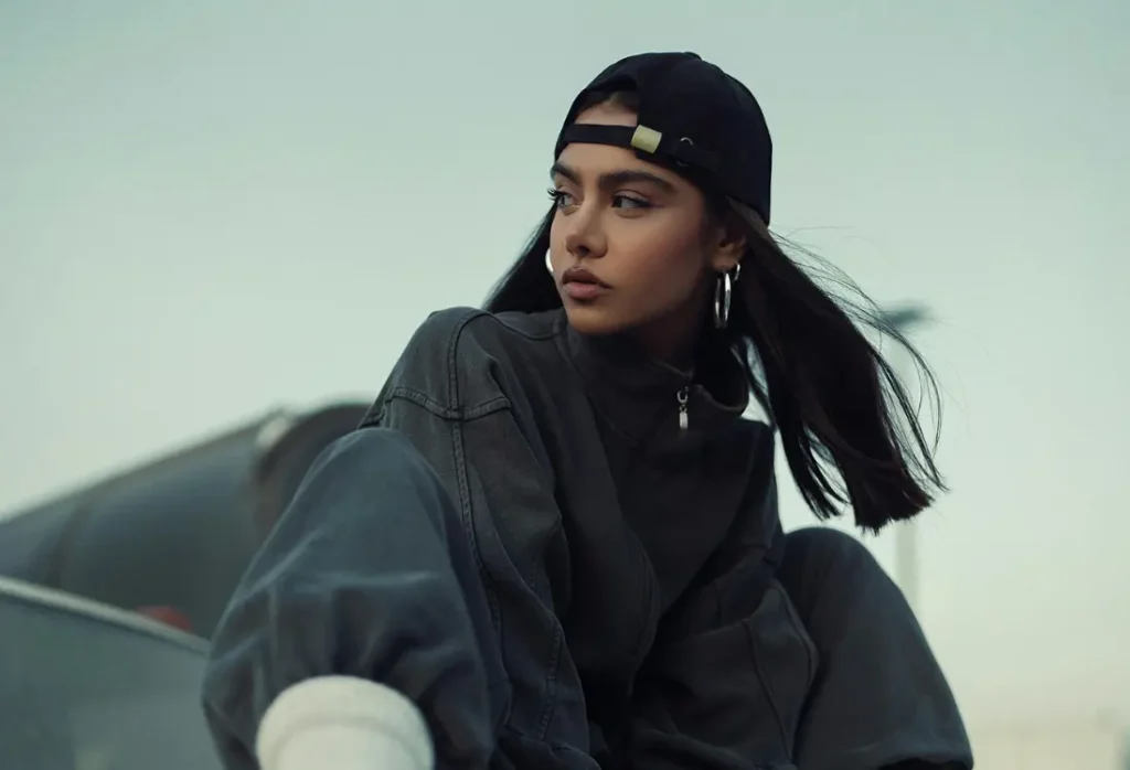 Woman wearing a black cap and relaxed dark streetwear, demonstrating how brands can take inspiration from gorpcore fashion to create clothing that feels at home in modern urban style.