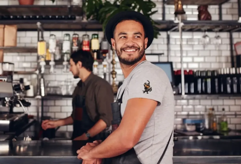 Barista wearing a comfortable branded T-shirt with a small Halloween graphic while working behind the counter.